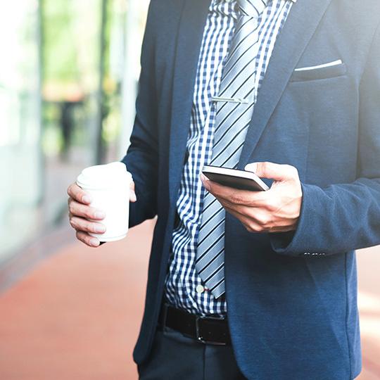 businessman holding a coffee and mobile phone