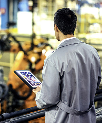 man surveying a workspace and holding a tablet